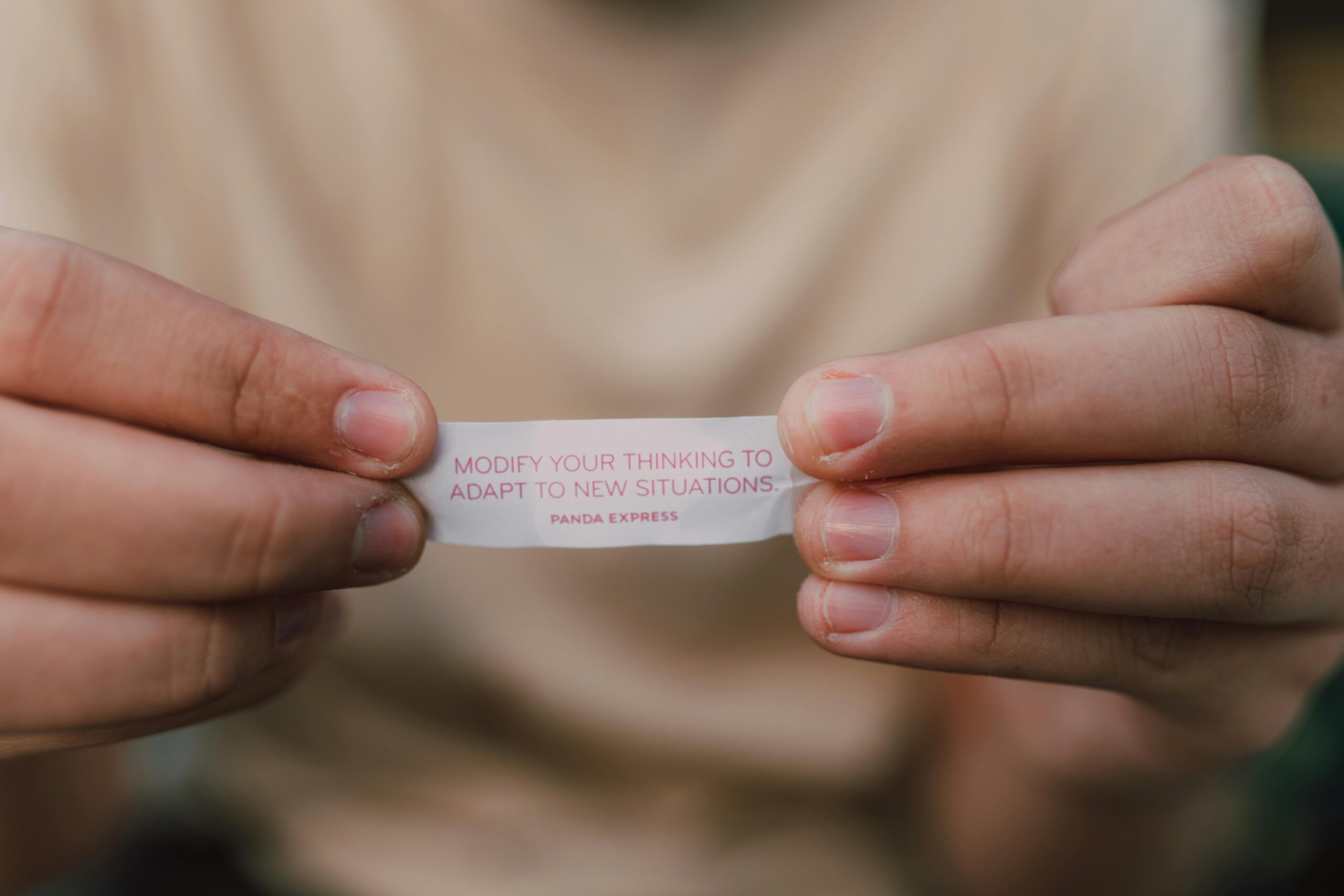 Close-up of hands holding a fortune cookie paper with insightful message