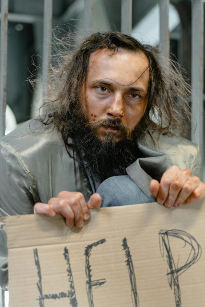 A man with facial hair holding a cardboard sign with 'HELP' written on it.